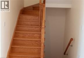 Mississauga townhouse for rent - A wooden staircase with a white wall on the side.