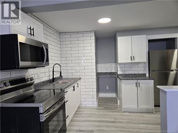 Moncton apartment for rent - A kitchen with white cabinets and black appliances.