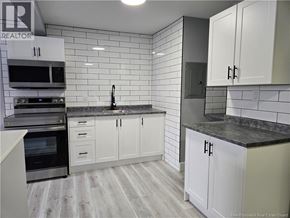 Moncton apartment for rent - A kitchen with white cabinets and a black countertop.