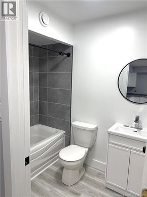 Moncton apartment for rent - A white toilet sits next to a white sink in a bathroom.