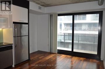 Toronto (Moss Park) condo for rent - A kitchen with a stainless steel refrigerator and a sliding glass door leading to a balcony.