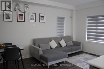 Brantford townhouse for rent - A living room with a grey couch and a dining table.