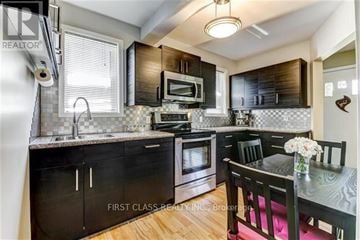 Toronto (Wexford-Maryvale) apartment for rent - A kitchen with black cabinets and a wooden table.