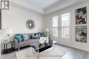 Oakville (Jm Joshua Meadows) townhouse for rent - A living room with a grey couch, a black coffee table, and a large sunburst mirror on the wall.