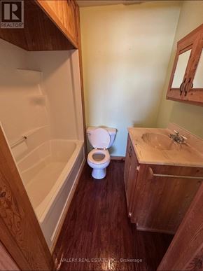 French River multi-family for rent - A white toilet sits in a bathroom with wooden cabinets and a bathtub.