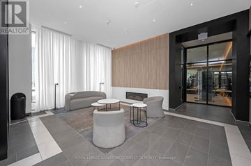 Hamilton (Beasley) condo for rent - A modern living room with a grey sofa and a black trash bin.