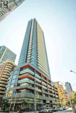 Toronto (Church-Yonge Corridor) condo for rent - A tall building with a blue and red stripe on the side stands out in a city street.