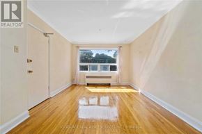 Toronto (Woodbine Corridor) apartment for rent - A room with wooden floors and a window overlooking a tree.