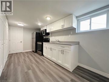 Kitchener apartment for rent - A kitchen with white cabinets and a wooden floor.