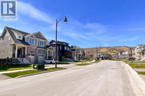Grey apartment for rent - A street view of a residential area with houses on both sides and a clear blue sky.