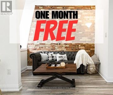 Toronto (Moss Park) multi-family for rent - A living room with a black couch and a brick wall with the words "ONE MONTH FREE" written on it.