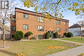 Windsor apartment for rent - A red brick building with a black fence and a tree with yellow leaves in front.