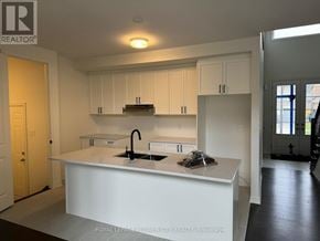 Adjala-Tosorontio (Colgan) townhouse for rent - A kitchen with white cabinets and a white island with a sink.