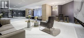 Toronto (Bayview Village) condo for rent - A modern living room with a grey sofa and a black chair.