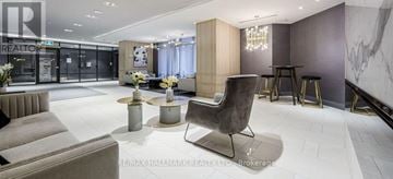 Toronto (Bayview Village) condo for rent - A modern living room with a grey sofa and a black chair.