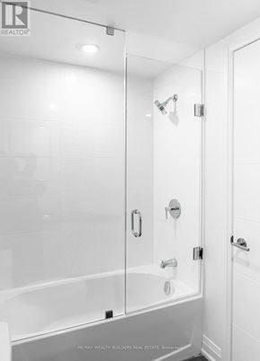 Toronto (Moss Park) multi-family for rent - A white bathroom with a glass shower door and a white tub.