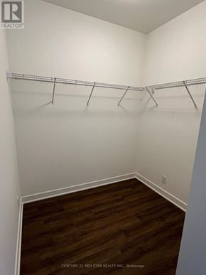 Clarington (Bowmanville) condo for rent - A room with white walls and wooden flooring with clothes hangers on the rail.