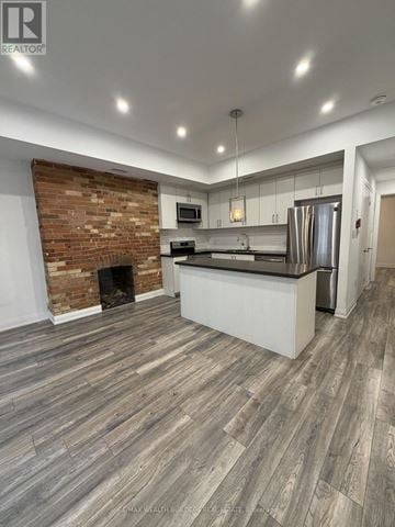 Toronto (Moss Park) townhouse for rent - A modern kitchen with a brick accent wall and wood flooring.