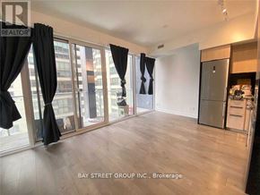 Toronto (Church-Yonge Corridor) condo for rent - A spacious room with a kitchen area and a view of the city through large windows.