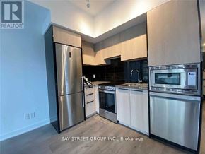 Toronto (Church-Yonge Corridor) condo for rent - A modern kitchen with stainless steel appliances and wooden cabinets.