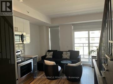 Toronto (Willowdale West) townhouse for rent - A living room with a black couch and a round mirror on the wall.