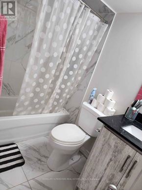 Brampton (Brampton South) apartment for rent - A white toilet sits in a bathroom with a shower curtain and a sink.