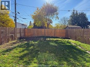 Windsor apartment for rent - A backyard with a wooden fence and green grass.