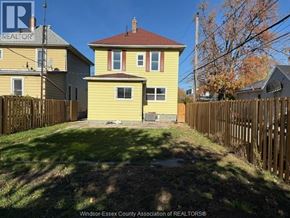 Windsor apartment for rent - A yellow house with a brown roof is surrounded by a wooden fence.