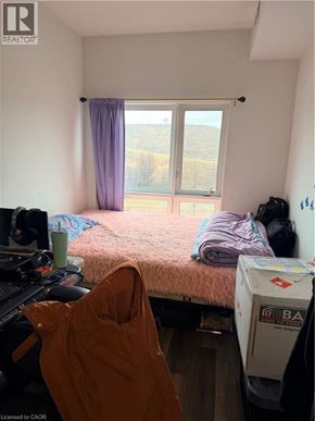 Kitchener townhouse for rent - A bedroom with a bed, a window with a purple curtain, and a white fridge.