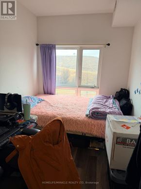 Kitchener townhouse for rent - A bedroom with a bed, a window, and a backpack on the floor.
