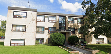 Oshawa apartment for rent - A large building with a green lawn in front.