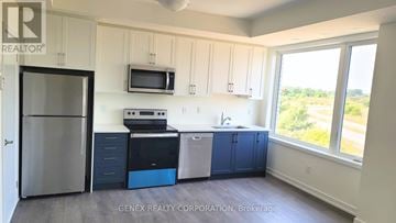 Cobourg townhouse for rent - A kitchen with white cabinets and a blue dishwasher.