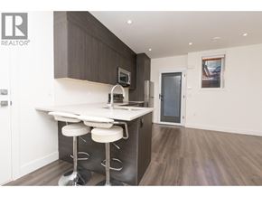 Burnaby apartment for rent - A modern kitchen with a bar stool and a fridge.