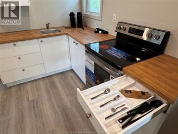 Windsor apartment for rent - A kitchen with a stove top oven and a drawer of utensils.