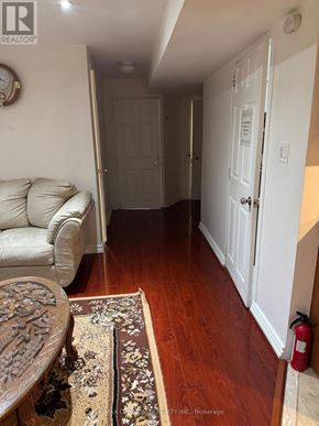 Toronto (Rouge) apartment for rent - A hallway with a white couch and a rug with a wooden floor.
