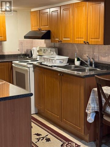 Toronto (Rouge) apartment for rent - A kitchen with wooden cabinets and a black range hood.