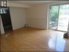 Toronto (L'amoreaux) apartment for rent - A room with wooden flooring and a sliding glass door leading to a backyard.