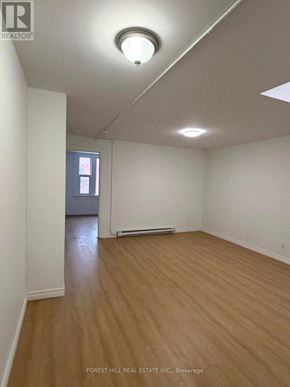 Kitchener apartment for rent - A room with wooden flooring and white walls, with a window and a door visible in the background.