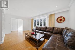 Oakville (Oo Old Oakville) apartment for rent - A brown leather couch sits in a spacious living room with a coffee table in front of it.