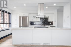 Collingwood condo for rent - A modern kitchen with white cabinets and a stainless steel refrigerator.