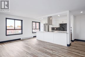 Collingwood condo for rent - A modern kitchen with white cabinets and a wooden floor.