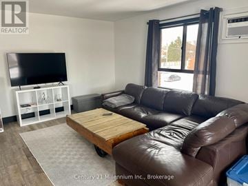 Collingwood condo for rent - A living room with a brown leather couch and a flat screen TV.