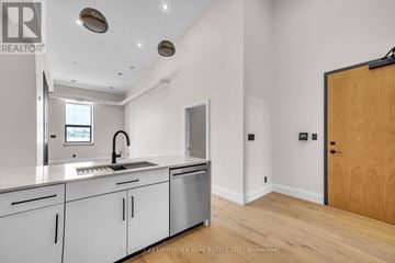 Quinte West (Trenton Ward) multi-family for rent - A modern kitchen with white cabinets and a wooden door.