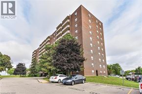 Kitchener condo for rent - A tall brown building with a parking lot in front of it.