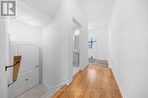 Ottawa townhouse for rent - A white hallway with wood flooring and a door on the left.