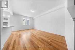 Ottawa townhouse for rent - A spacious room with wooden flooring and white walls.