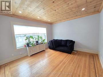 Hamilton (Gibson) townhouse for rent - A living room with a black couch and a window with plants on a table.