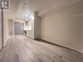 Vaughan (Vaughan Corporate Centre) condo for rent - A spacious room with wood flooring and a kitchen area in the background.