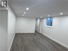 Kitchener apartment for rent - A spacious room with wooden flooring and white walls.