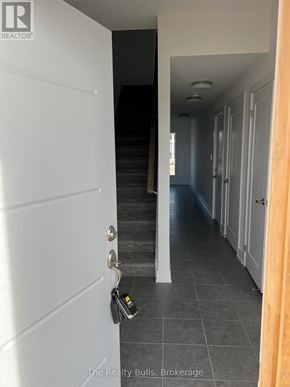 Stratford townhouse for rent - A hallway with a white door and a black staircase.